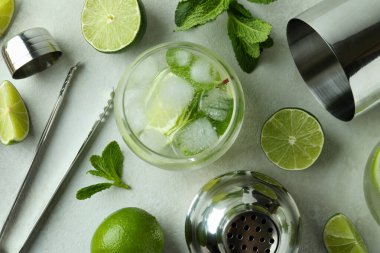 Bir bardak mojito kokteyli ve beyaz desenli masa malzemeleri.
