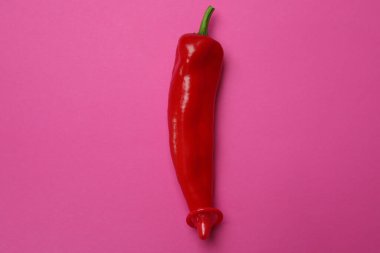 Pembe arka planda kırmızı prezervatifli kırmızı biber.