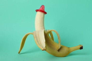 Arka planda kırmızı prezervatifli muz.