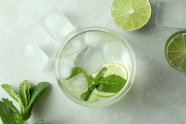 Bir bardak mojito kokteyli ve beyaz desenli masa malzemeleri.