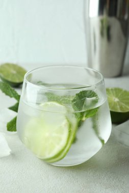 Bir bardak mojito kokteyli ve beyaz desenli masa malzemeleri.
