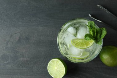 Bir bardak mojito kokteyli ve koyu ahşap masa malzemesi.