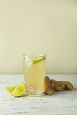 Bir bardak zencefilli bira ve malzemeler beyaz ahşap masada.