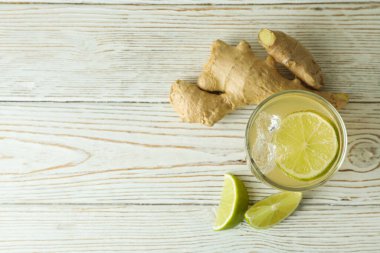 Bir bardak zencefilli bira ve malzemeler beyaz ahşap masada.