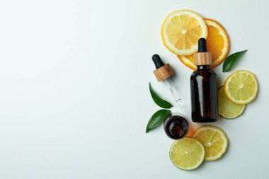 Beyaz arka planda yağ ve narenciye dilimleri olan damlalar.