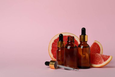 Pembe arka planda yağlı ve greyfurt dilimli damlalar.