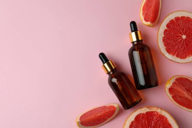 Pembe arka planda yağlı ve greyfurt dilimli damlalar.