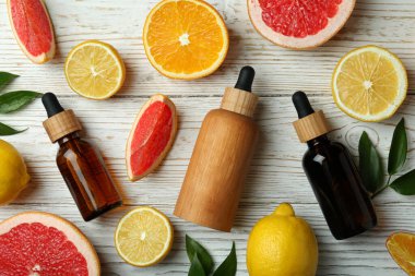 Yağlı damlalar ve beyaz ahşap arka planda farklı turunçgiller.