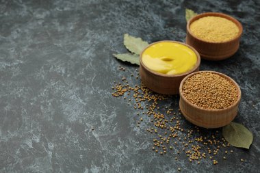 Siyah dumanlı arka planda hardal tohumu, sos ve toz dolu kaseler.
