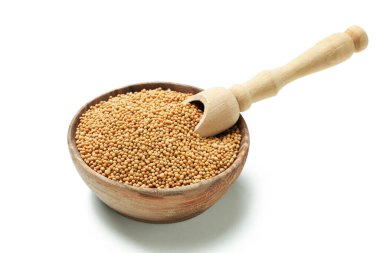 Beyaz arka planda hardal tohumları ve kepçeyle izole edilmiş kase