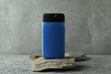 Bir şişe duş jeli taşın üzerinde gri desenli masada.