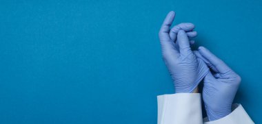 Doctor hands in medical gloves on blue background clipart