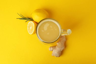 Bir bardak zencefilli bira ve sarı arka planda malzemeler.