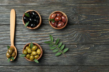Farklı zeytin ve kaşık kâseleriyle ahşap kaplanmış zeytinler.
