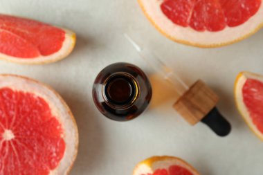 Beyaz desenli arka planda yağ ve greyfurtlu damlacık şişesi.