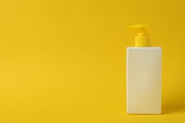 Sarı arkaplanda bir şişe güneş kremi, metin için boşluk