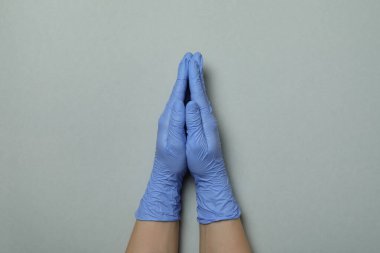Avuçlar tıbbi eldivenlerle açık gri arka planda