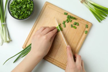 Beyaz arka planda yeşil soğan dilimleyen kadın.