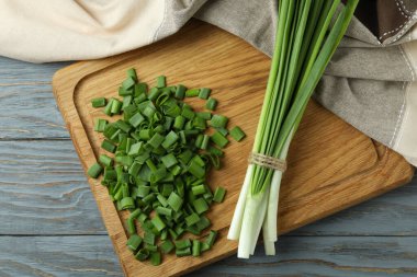 Taze yeşil soğan kesim tahtasında, gri ahşap masada.