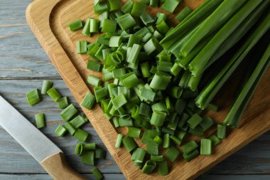 Taze yeşil soğan kesim tahtasında, gri ahşap masada.