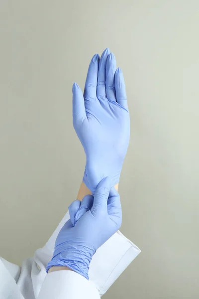 Médico Poniendo Guantes Médicos Sobre Fondo Gris Claro — Foto de Stock