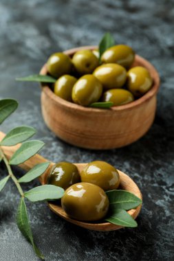 Kase dolusu zeytin ve siyah dumanlı arka planda yapraklar.