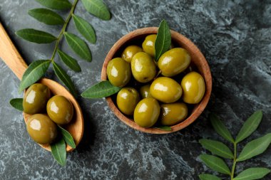 Kase dolusu zeytin ve siyah dumanlı arka planda yapraklar.