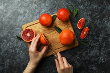 Kadın gemide siyah dumanlı bir arka planda bir portakal kesiyor.