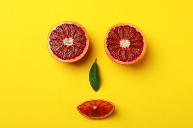 Sarı arkaplanda kırmızı portakallardan yapılmış yüz