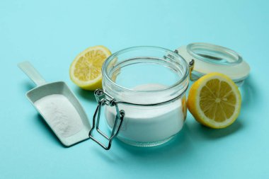 Mavi arka planda asit tozu ve yarım limon ile kepçe ve kavanoz