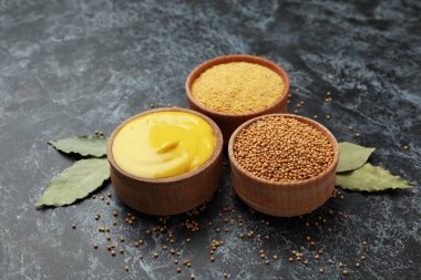 Siyah dumanlı arka planda hardal tohumu, sos ve toz dolu kaseler.