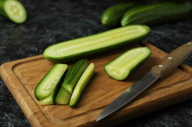 Olgun salatalık ve siyah dumanlı masada bıçak.