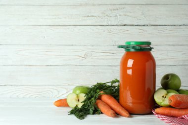 Bir kavanoz elma - havuç suyu ve beyaz ahşap arka planda malzemeler