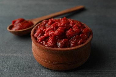 Koyu ahşap arka planda domates ezmeli ahşap kase ve kaşık.