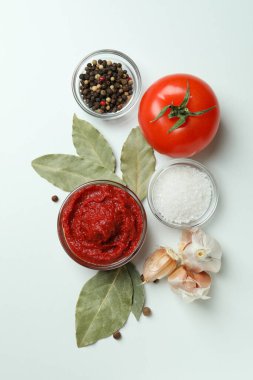 Beyaz zemin üzerinde domates ezmesi ve malzemelerle dolu bir kase.