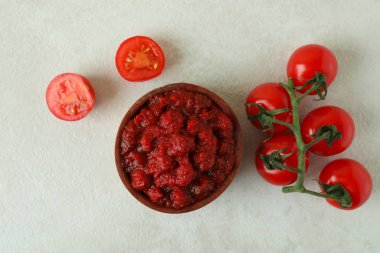 Tahta kase, domates ezmesi ve domatesler beyaz desenli masa.