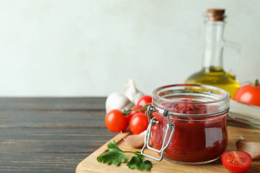 Domates ezmeli kavanoz ahşap masada malzemelerle.