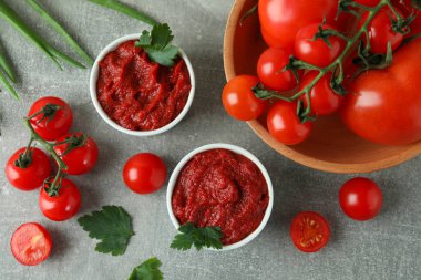 Gri arka planda domates ezmeli kaseler ve malzemeler.