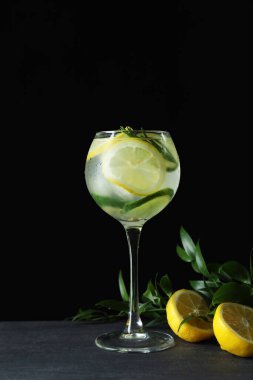 Koyu arkaplanda turunçgil olan bir bardak kokteyl.