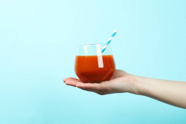 Mavi arka planda kadın meyve suyu bardağı var.