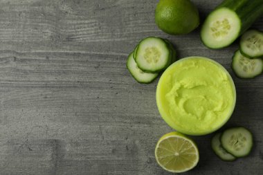 Gri desenli arka planda kozmetik, salatalık ve limon içeren kavanoz.