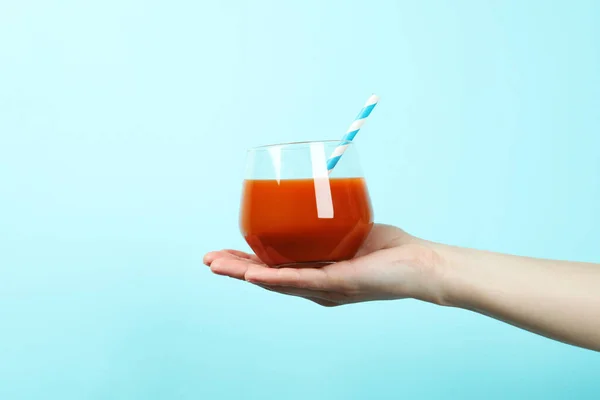 Female hand hold glass of juice on blue background