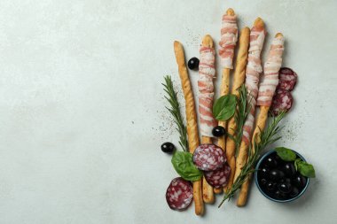 Grissini pastırmalı çubuklar ve beyaz desenli arka planda atıştırmalıklar.