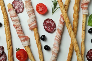 Grissini pastırmalı çubuklar ve beyaz arka planda atıştırmalıklar.