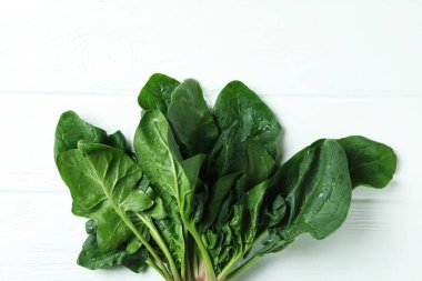 Beyaz ahşap arka planda taze çiğ ıspanak.