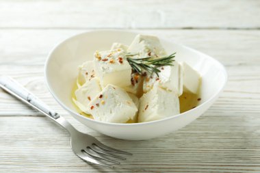 Beyaz ahşap arka planda beyaz peynir ve çatalla kase