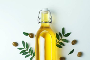 Beyaz arka planda bir şişe yağ, zeytin ve dal.