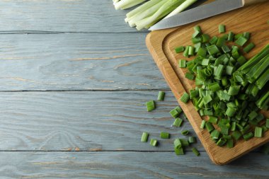 Taze yeşil soğan kesim tahtasında, gri ahşap masada.