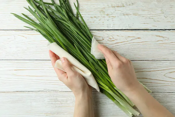 Mani Femminili Tengono Asciugamano Cucina Con Cipolla Verde Sfondo Legno — Foto Stock
