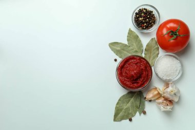 Beyaz zemin üzerinde domates ezmesi ve malzemelerle dolu bir kase.